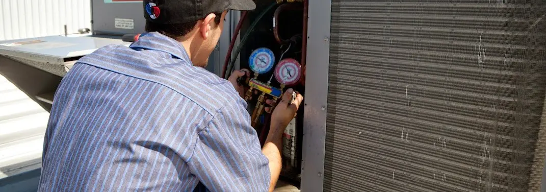 HVAC technician servicing a condenser unit in Enumclaw